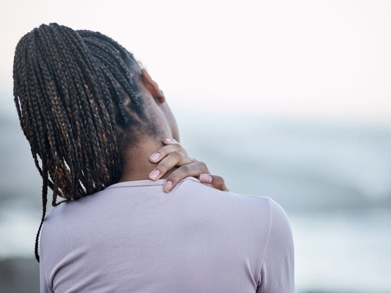 Kvinna tar sig på nackområdet. Verkar ha ont