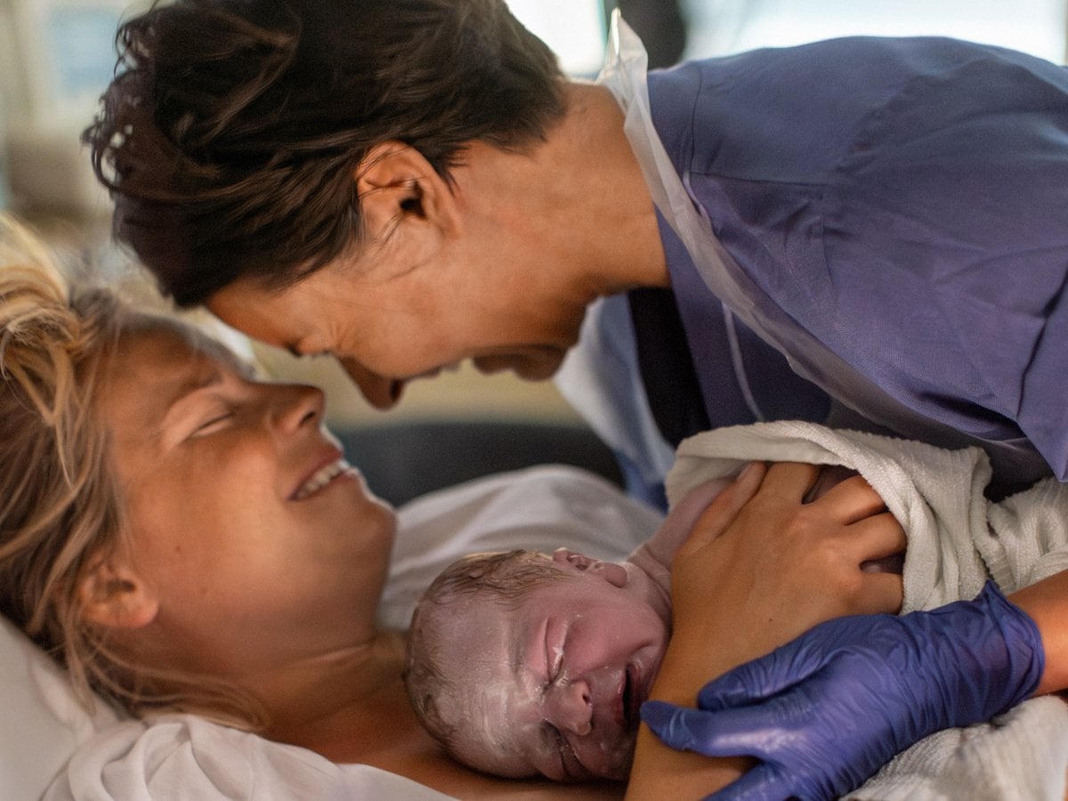 En kvinna håller i en bebis i en sjukhussäng.