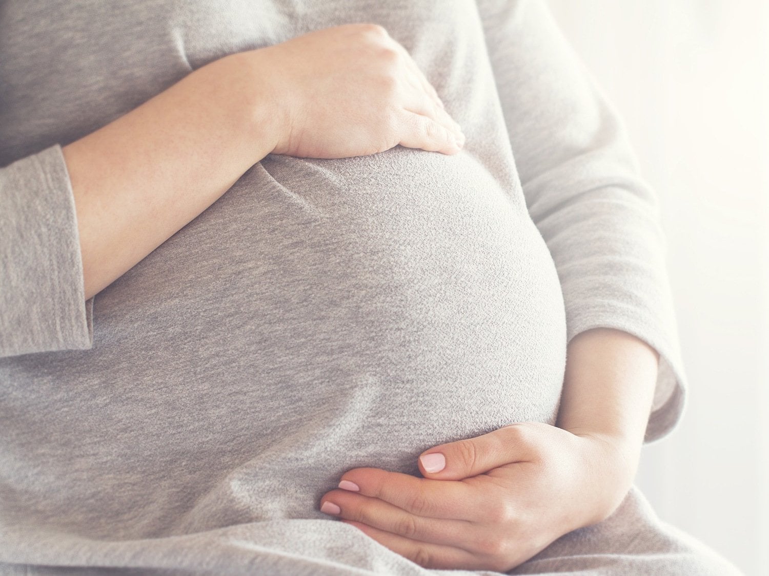 En gravid kvinna som håller om sin mage med sina händer. 