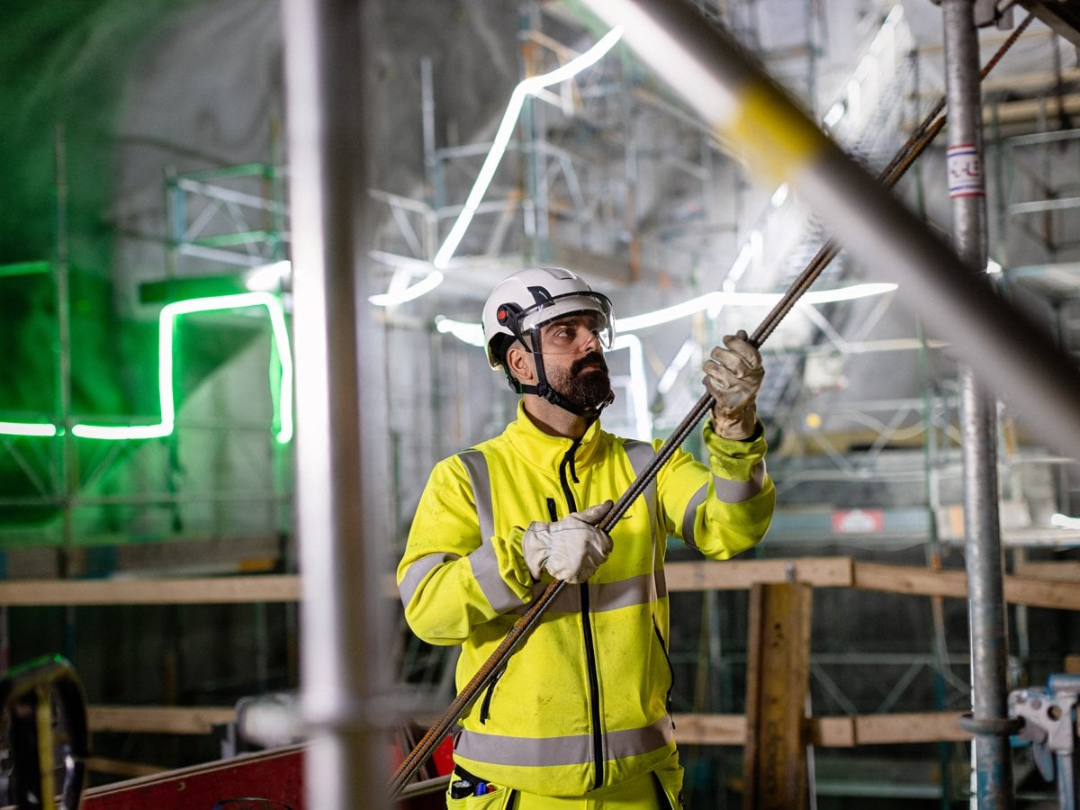 En man i gul jacka som håller i ett stort rör.