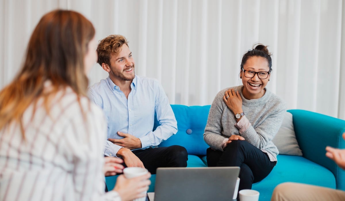 Kollegor sitter i en turkos soffa.