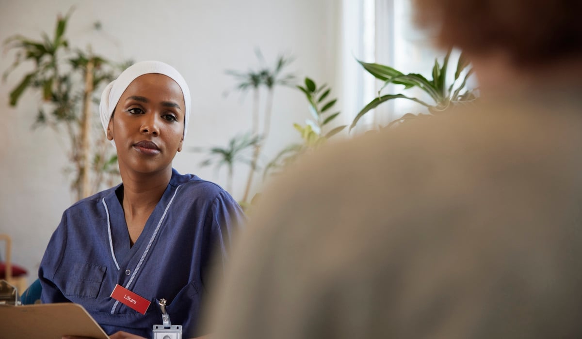 En läkare sitter och pratar med en patient. 