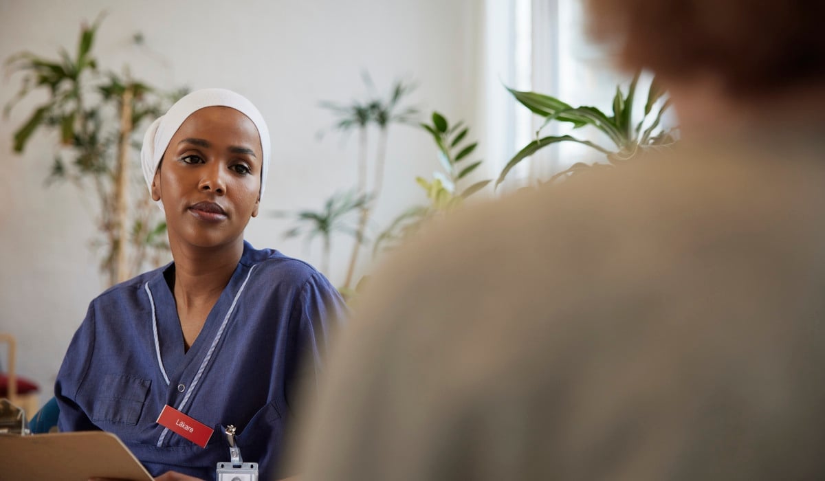 En läkare sitter och pratar med en patient. 