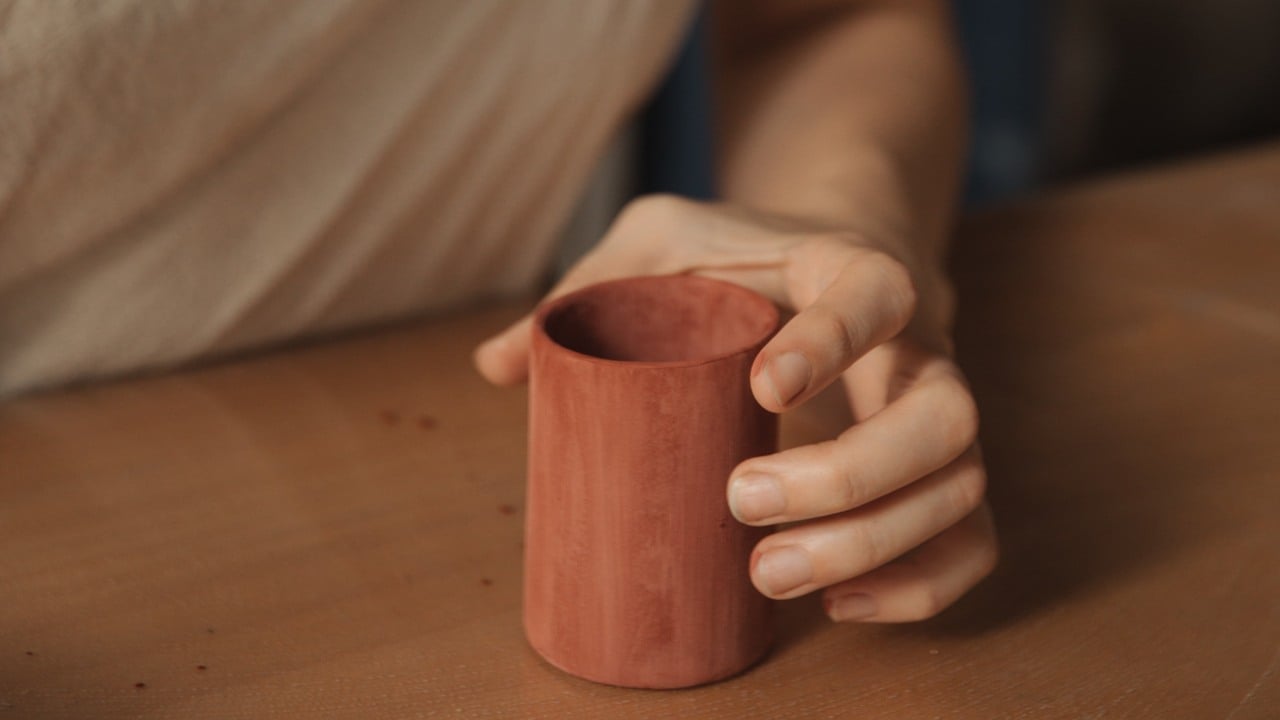 En person håller i en bägare av trä