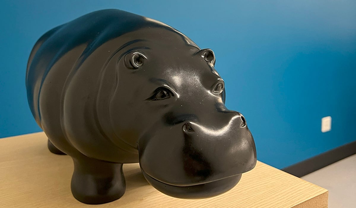 En skulptur i form av en liten hippo som står på ett podium.