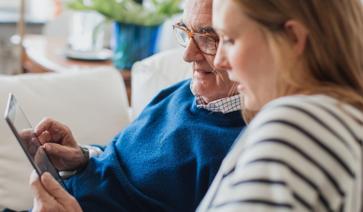 Två personer som sitter bredvid varandra och tittar på en surfplatta.