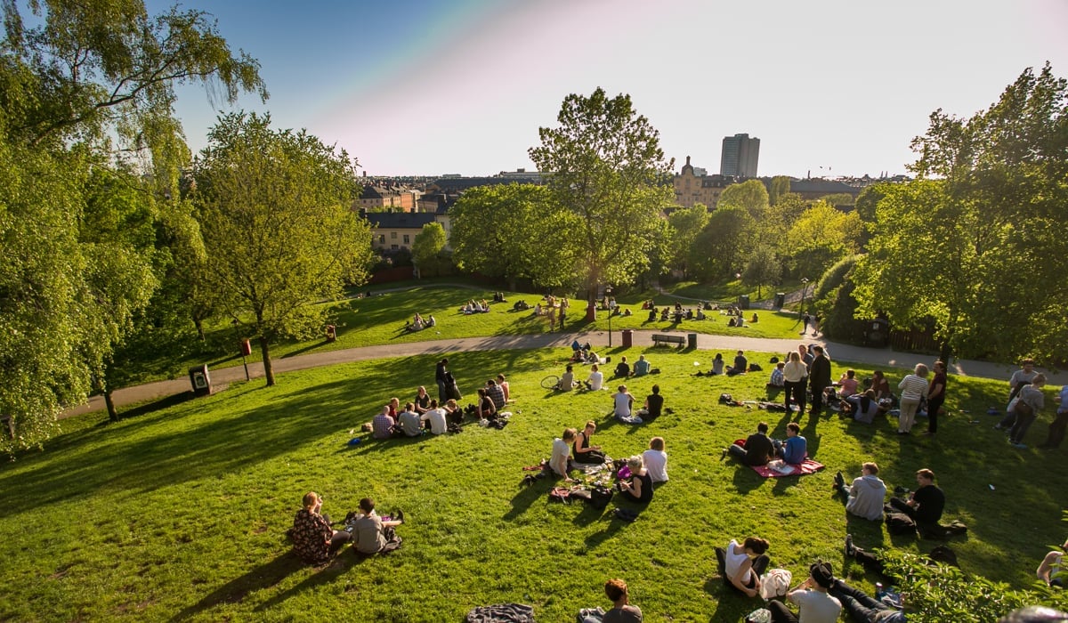 Foto på en park där människor sitter på filtar. 