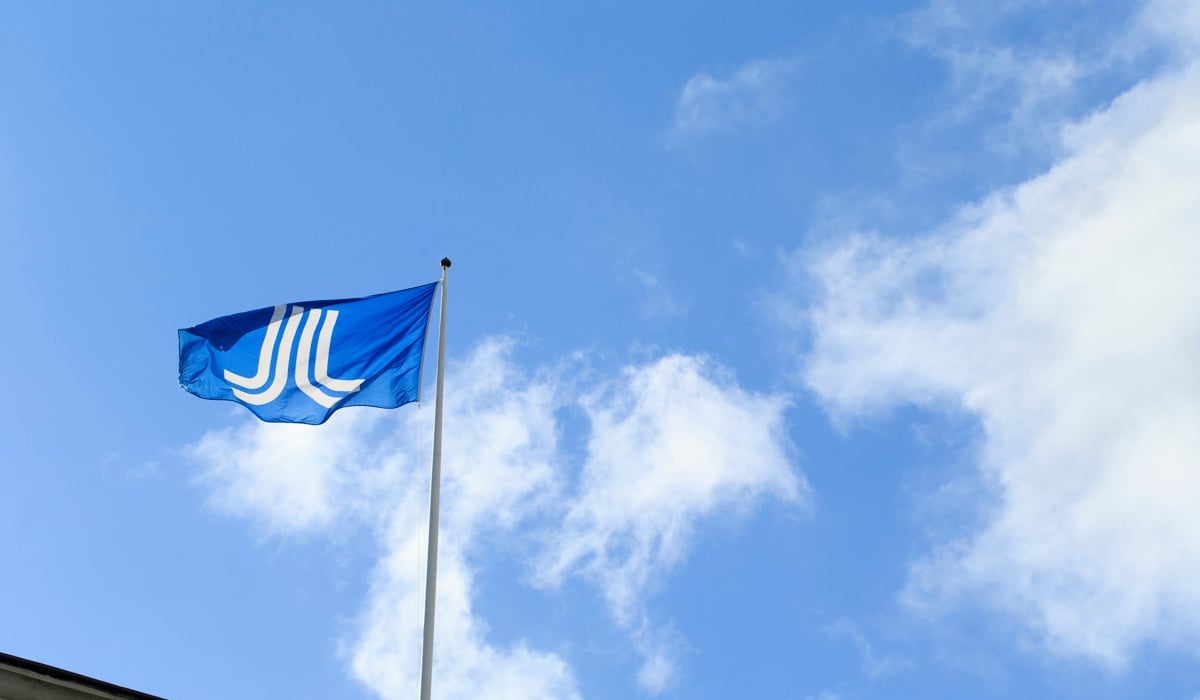 En Region Stockholm-flagga som vajar i skyn.