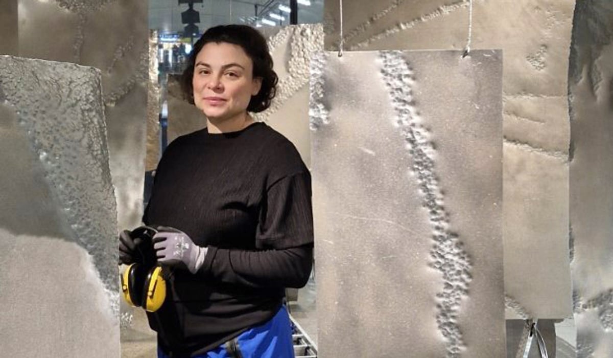 En kvinna står framför en skulptur.