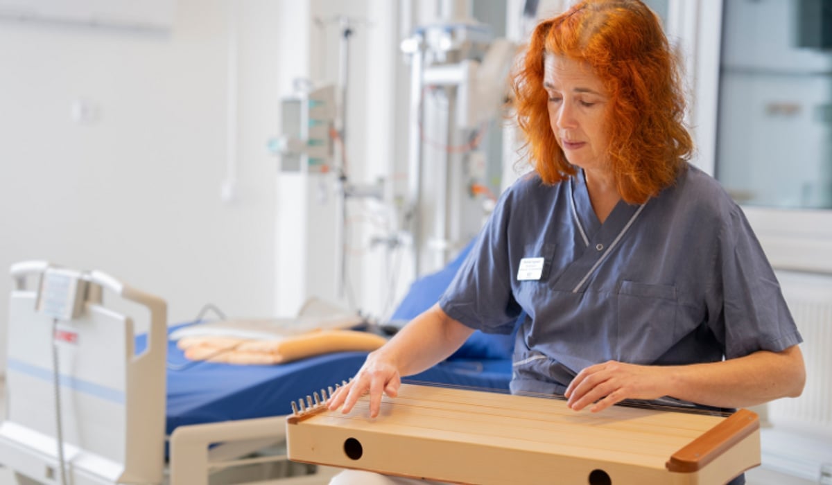 Pernilla sitter med instrument i knät. Bakom skymtar en sjukhussäng.