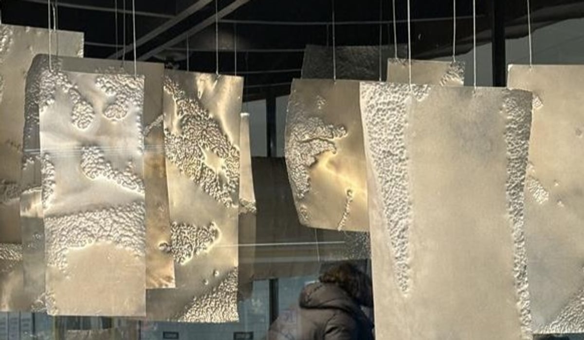 En kvinna sitter på huk i en utställning av konst.