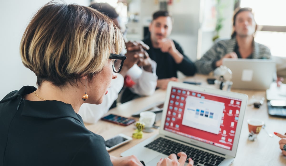 Personer samtalar vid ett möte samtidigt som de jobbar med sina datorer