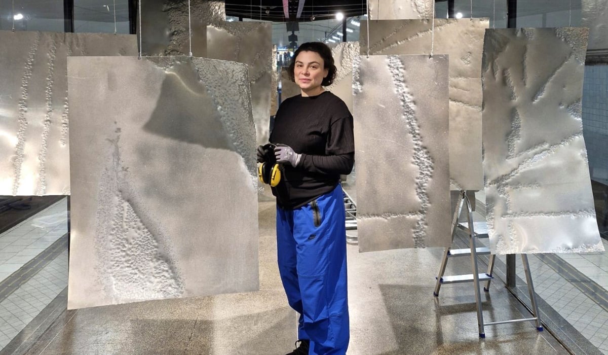 En kvinna står framför en skulptur.