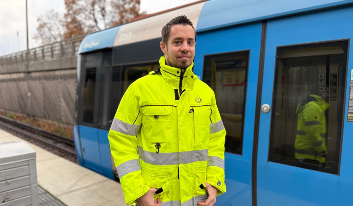 En man står framför ett blått tåg.