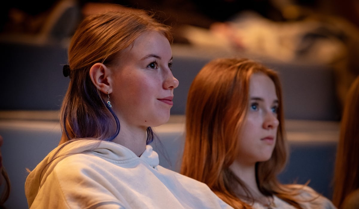 Två tonårsstjejer sitter i en biosalong och tittar på film