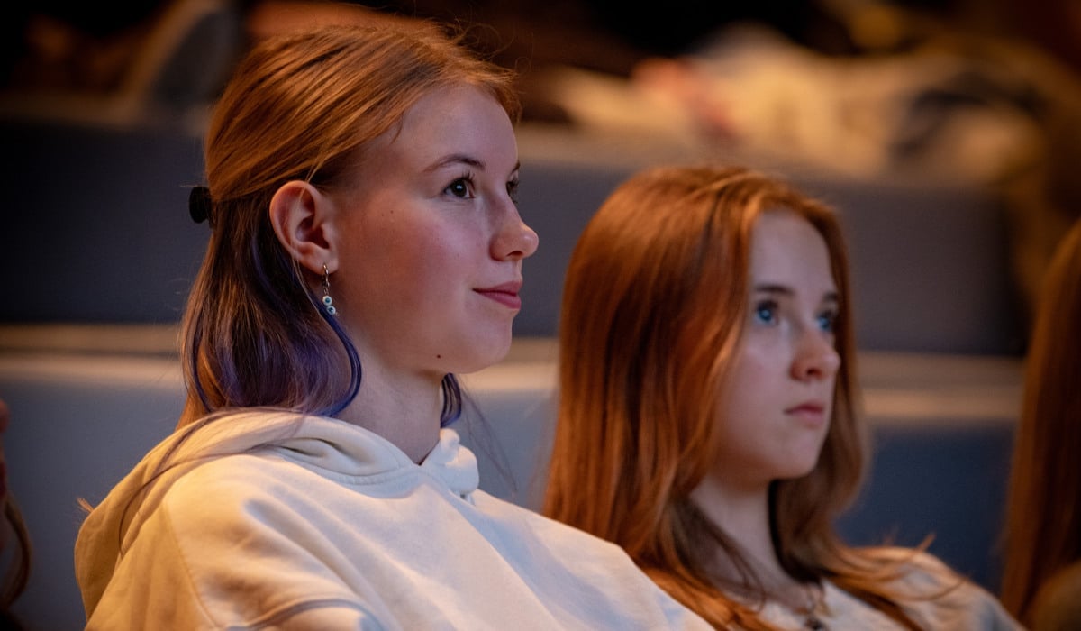 Två tonårsstjejer sitter i en biosalong och tittar på film