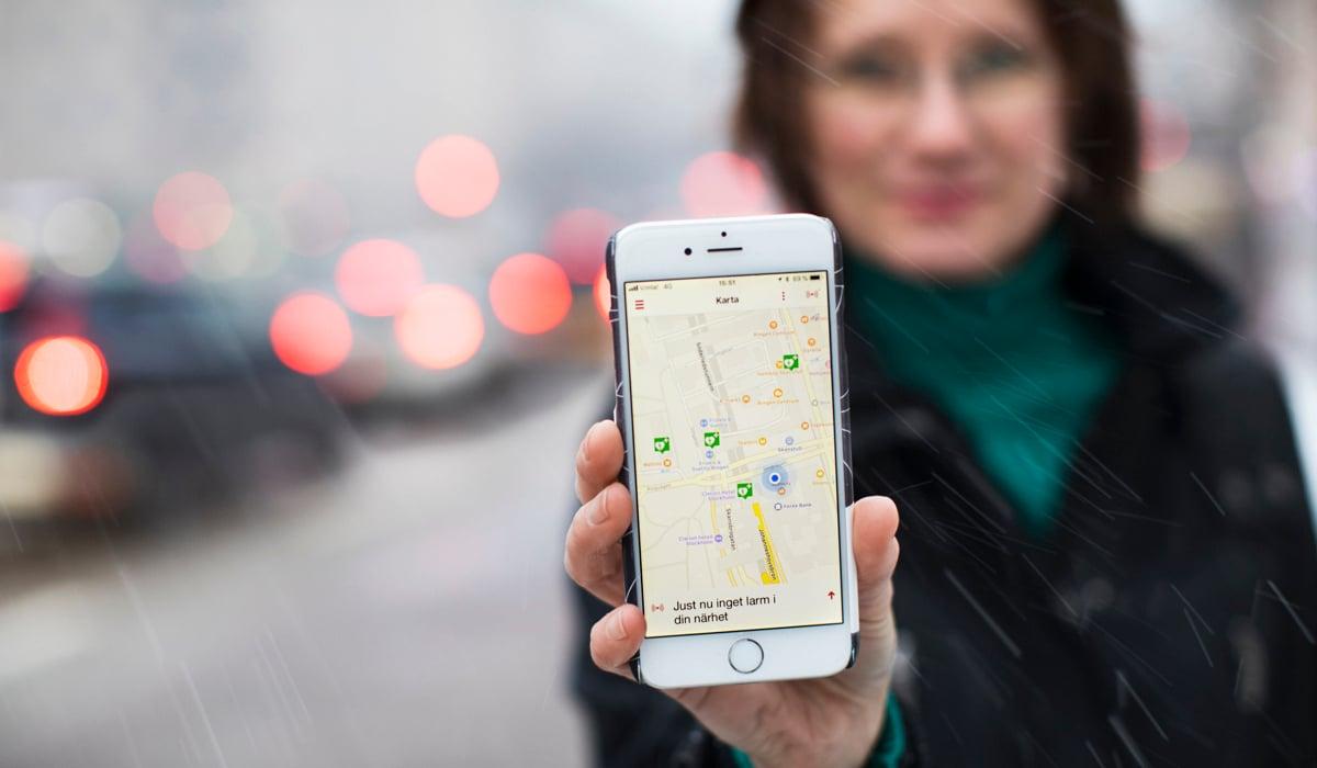 Foto på kvinna som håller i en mobiltelefon som visar en karta. 