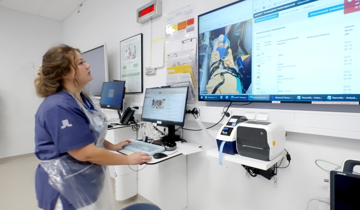 En kvinna i sjukhuskläder står och läser på en skärm