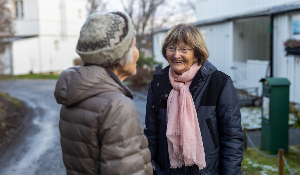 Två äldre kvinnor står och pratar med varandra.