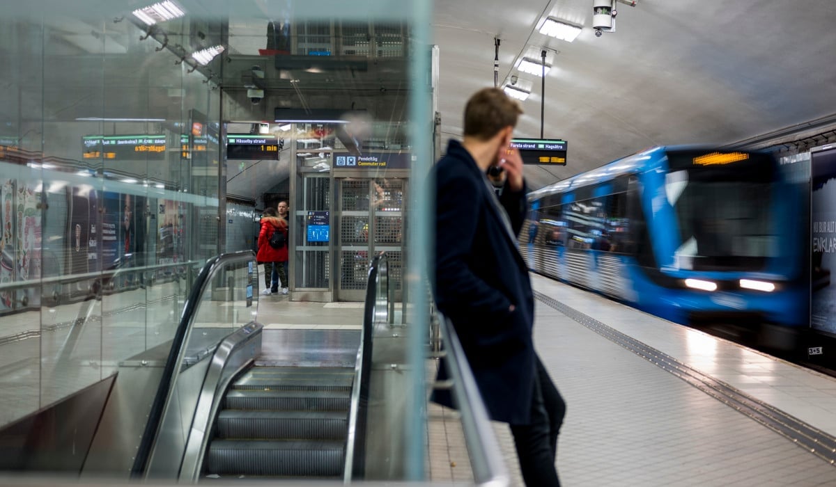 Personer väntar på tunnelbanan som rullar in i hög fart