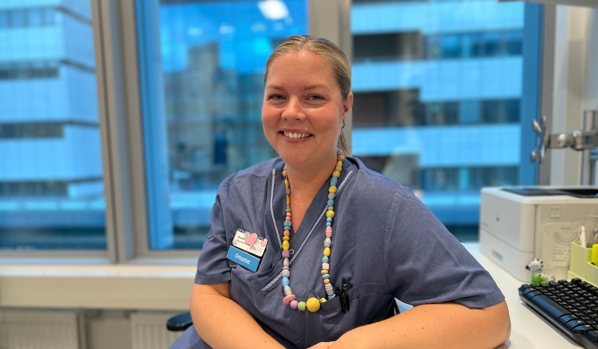 En kvinna i operationskläder sitter vid ett skrivbord.