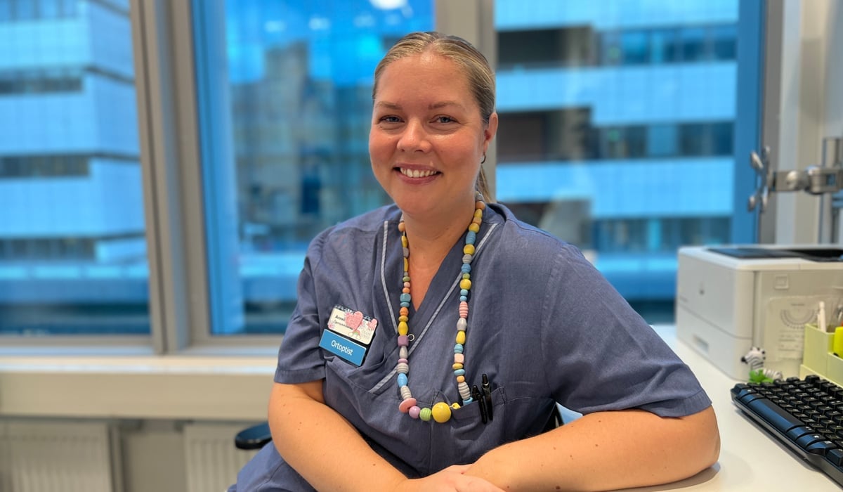 En kvinna i operationskläder sitter vid ett skrivbord.