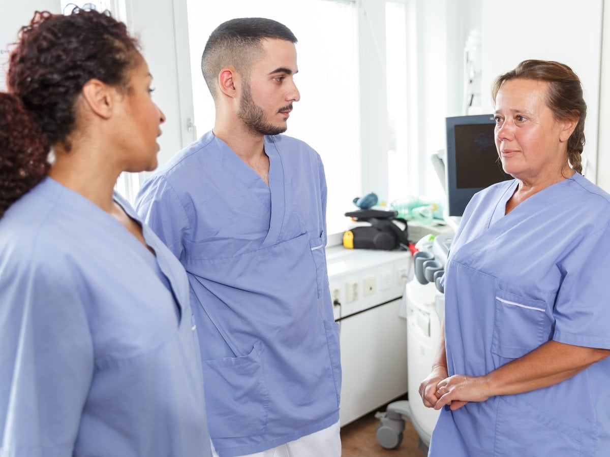 Foto på tre personer som bär sjukhuskläder.