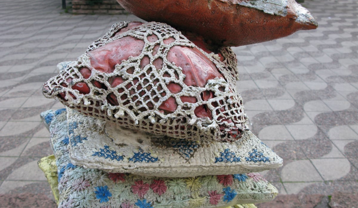 Skulptur i betong som föreställer virkade kuddar.