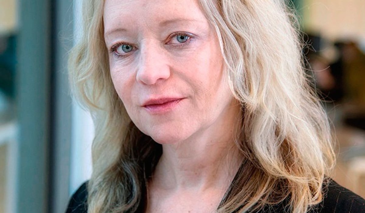 En kvinna med blont hår och svart skjorta.