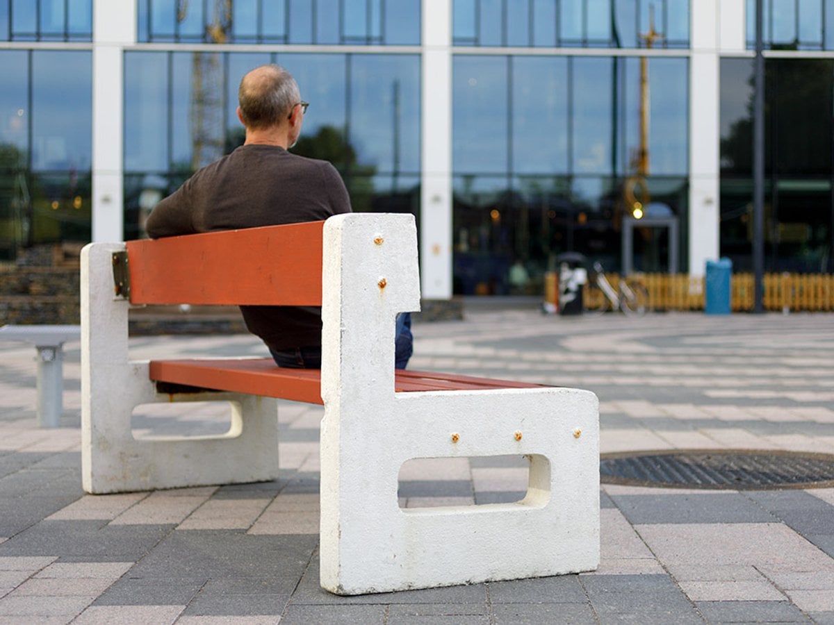 Man sitter på bänk framför Karolinska sjukhuset.