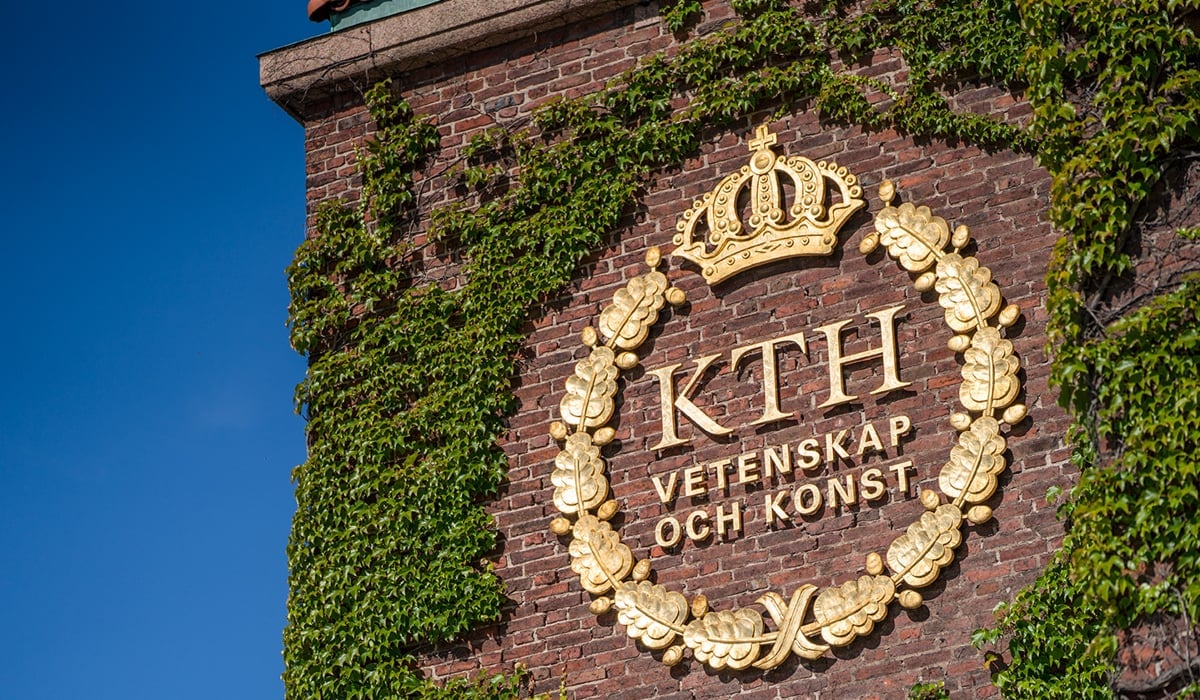 Foto på fasaden på Kungliga tekniska högskolan. På bilden syns en logga i guldfärg med växter runt omkring.