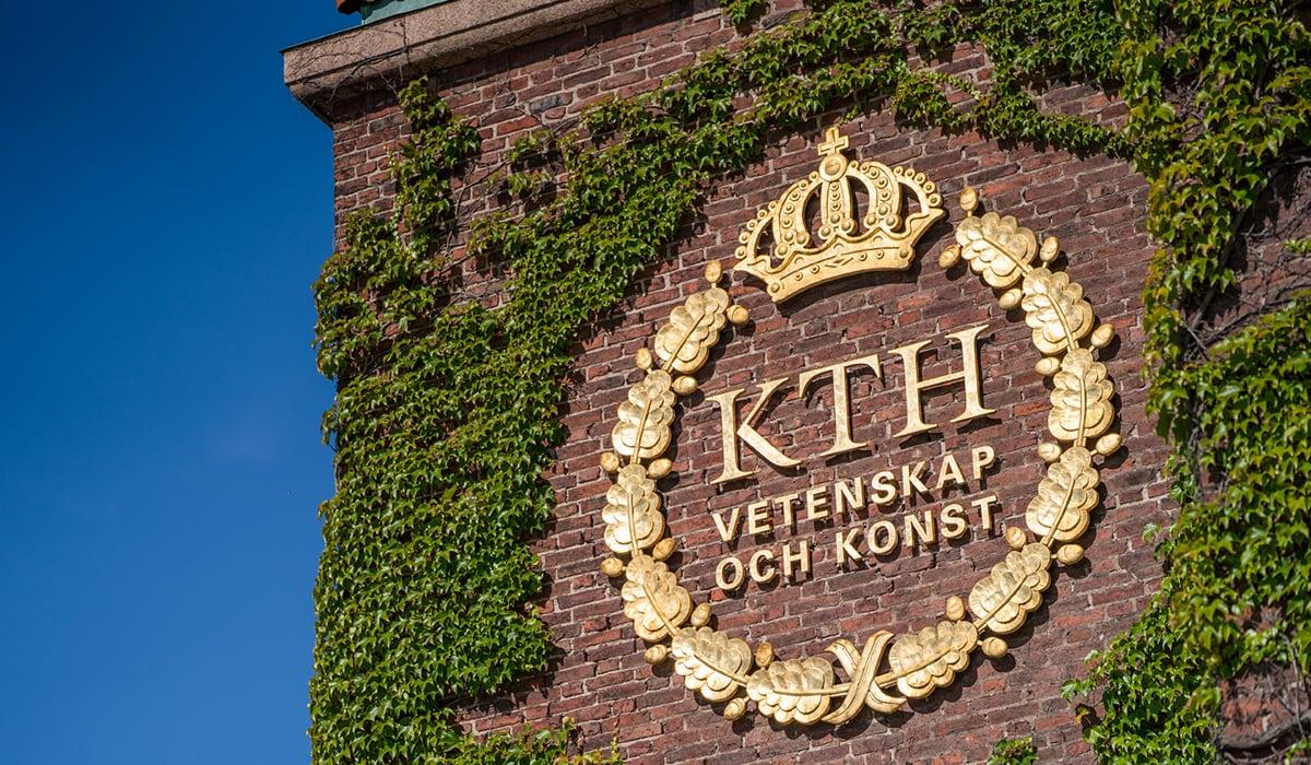 Foto på fasaden på Kungliga tekniska högskolan. På bilden syns en logga i guldfärg med växter runt omkring. 