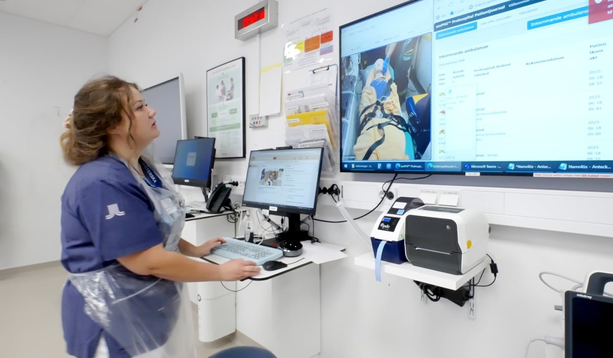 En kvinna i sjukhuskläder står och läser på en skärm