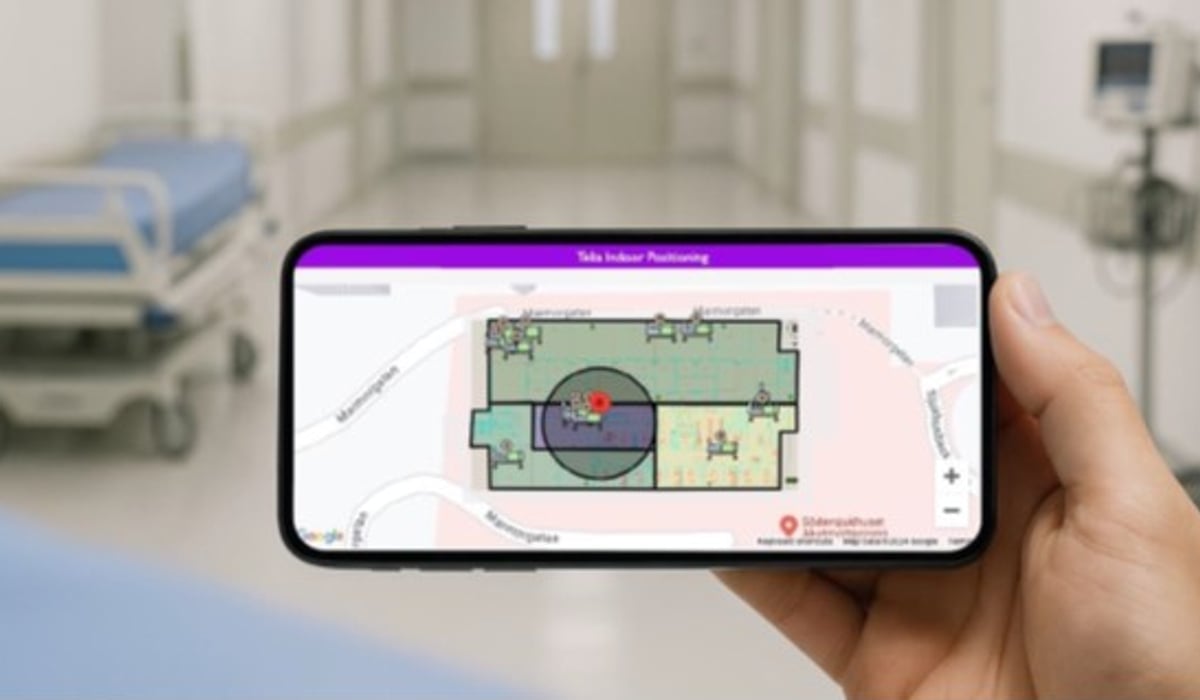 En hand håller i en mobiltelefon som visar en karta