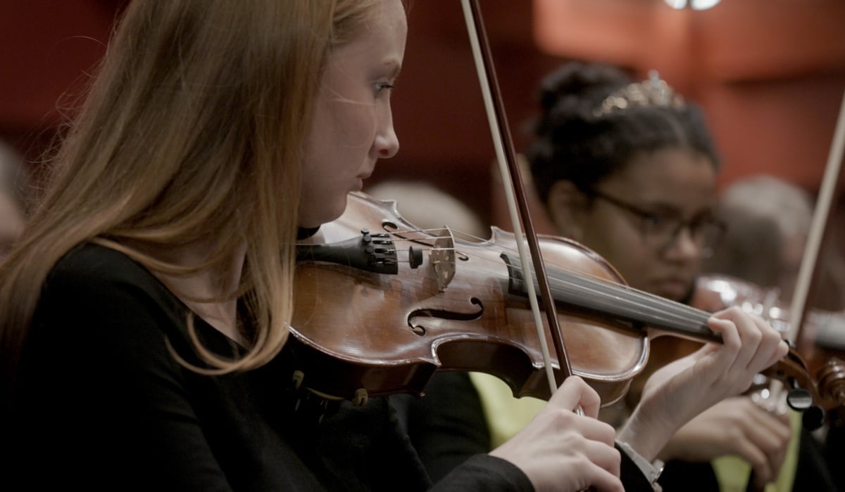 Två ungdomar spelar musik i en stor sal.
