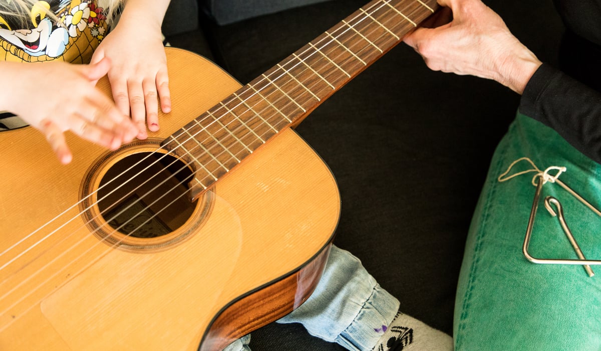 Händer som håller i en gitarr.