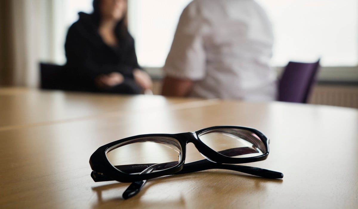 Ett par svarta glasögon som sitter på ett träbord.