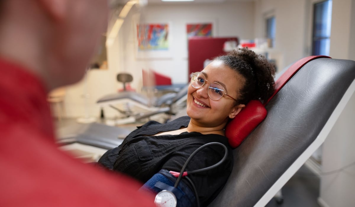 Kvinna ligger i besöksstol på blodgivarmottagning och får sitt blodtryck taget.