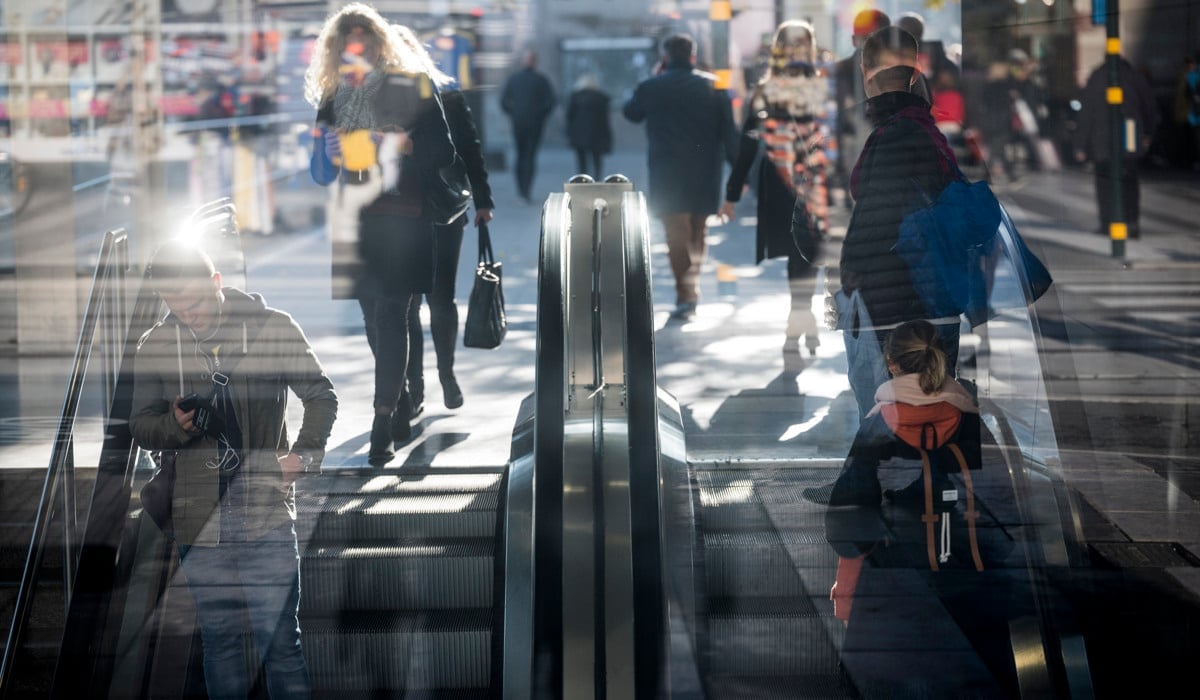 Bild på människor i och vid rulltrappor. Människorna är suddiga eftersom de är i rörelse.