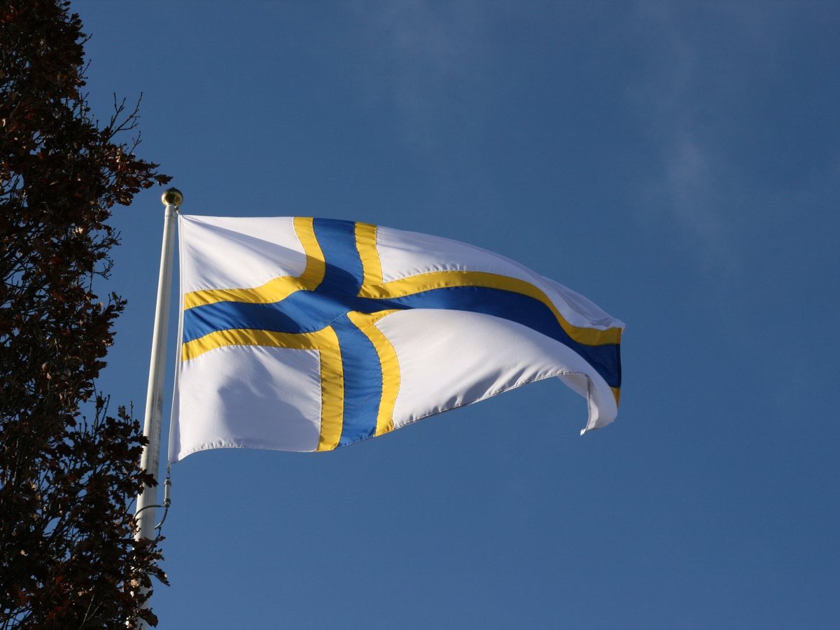 En sverigefinsk flagga som vajar i vinden en solig dag.