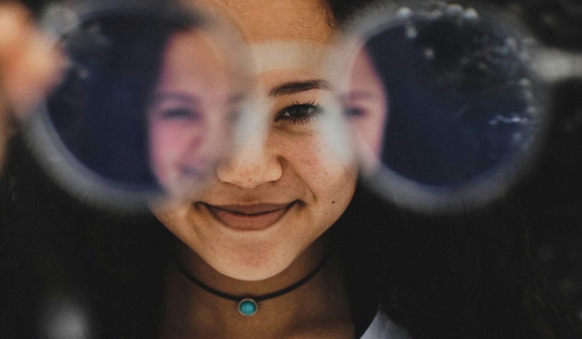 En flicka som tittar genom ett par glasögon.