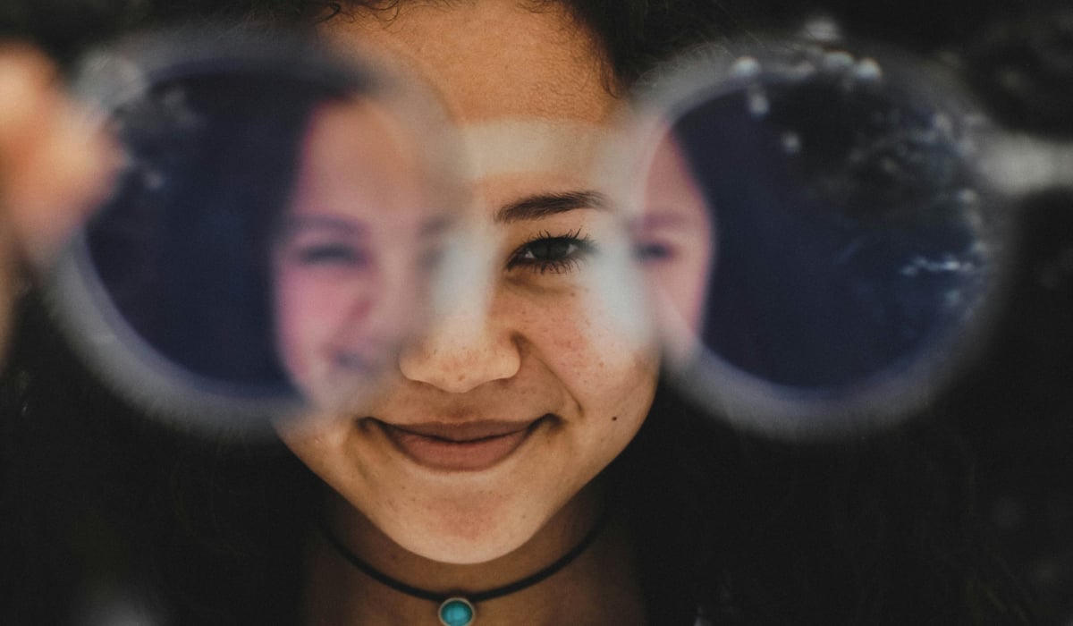 En flicka som tittar genom ett par glasögon.