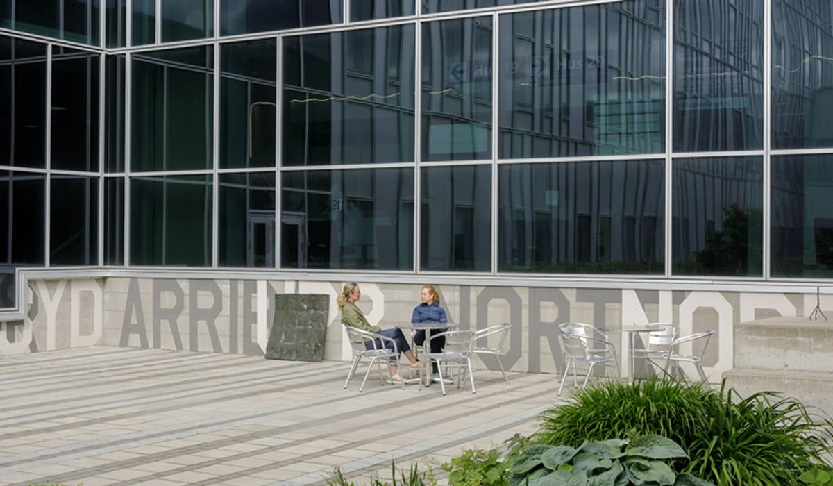 Några personer sitter vid ett bord utanför en byggnad.