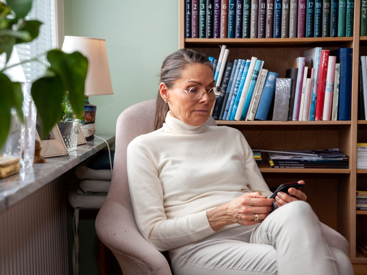 Kvinna sitter och tittar på sin mobil.