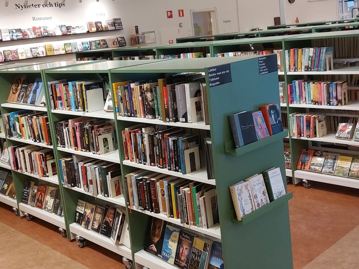 Interiör från Gribbylunds bibliotek. Gröna bokhyllor.
