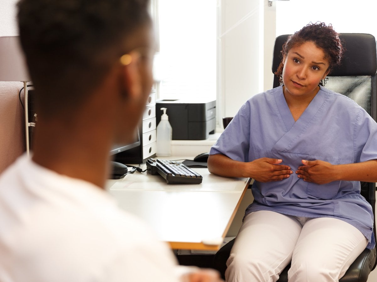 Kvinnlig läkare samtalar med ung manlig patient.