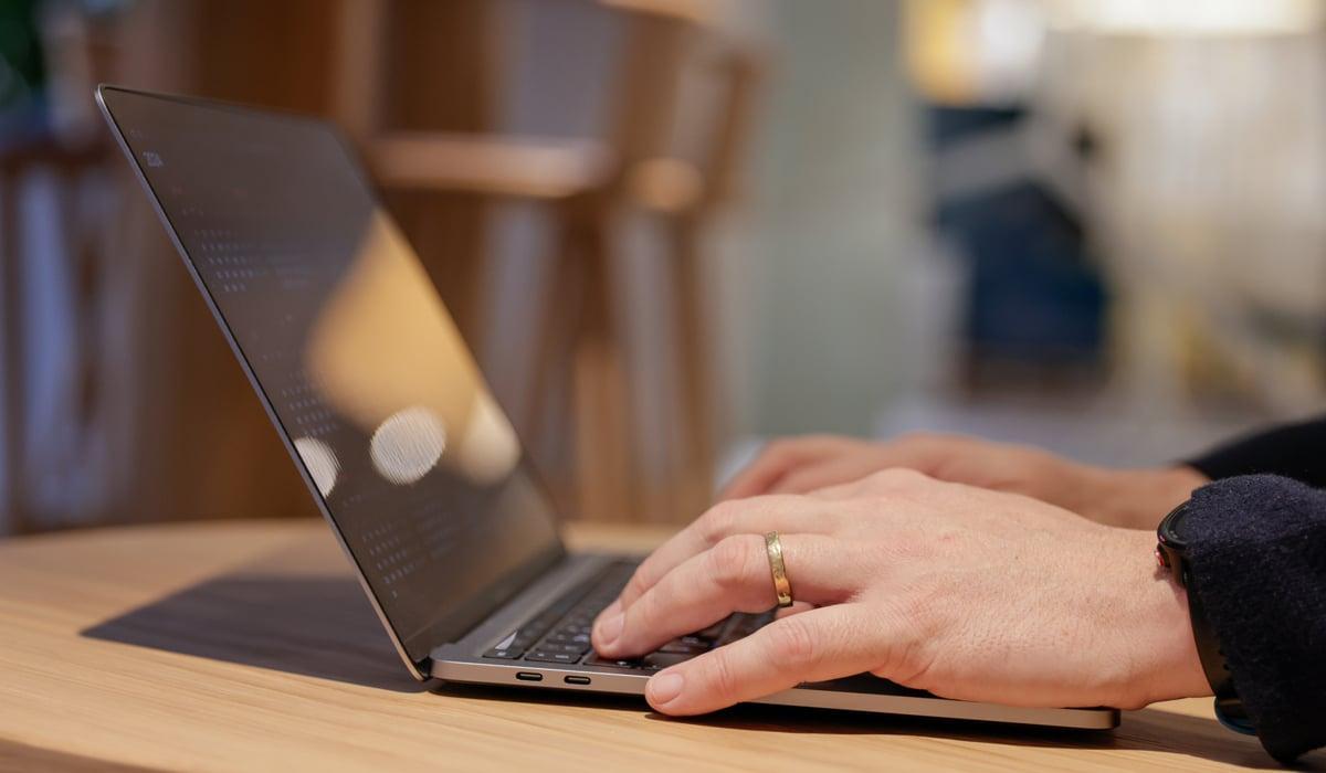 Närbild av två händer som skriver på laptop.
