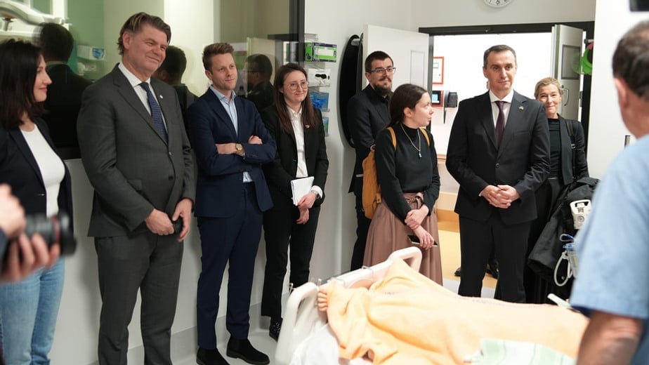 Personer som besöker Karolinska universitetssjukhuset. De samtalar med varandra i ett vårdrum.