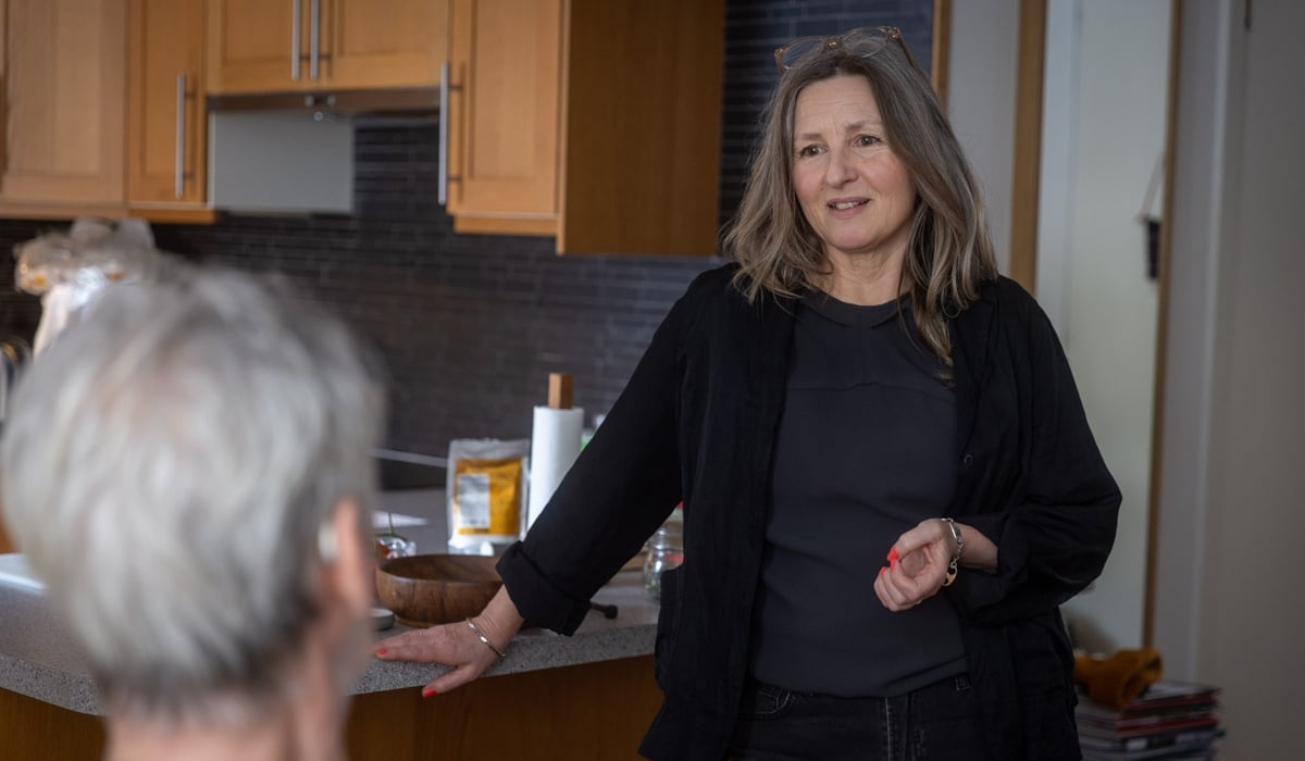 En kvinna pratar med en man i ett kök.