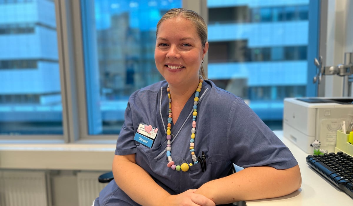 En kvinna i operationskläder sitter vid ett skrivbord.